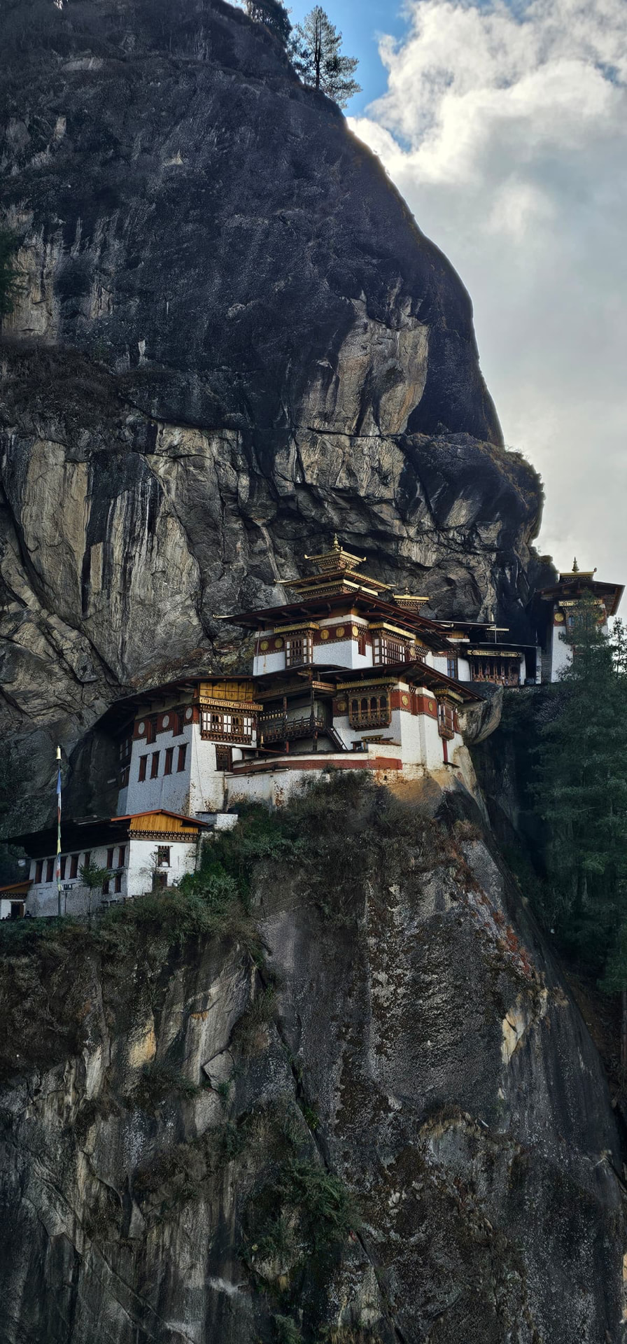Tiger's Nest Monastery clinging to a dramatic dark cliff amid mist and sunlight