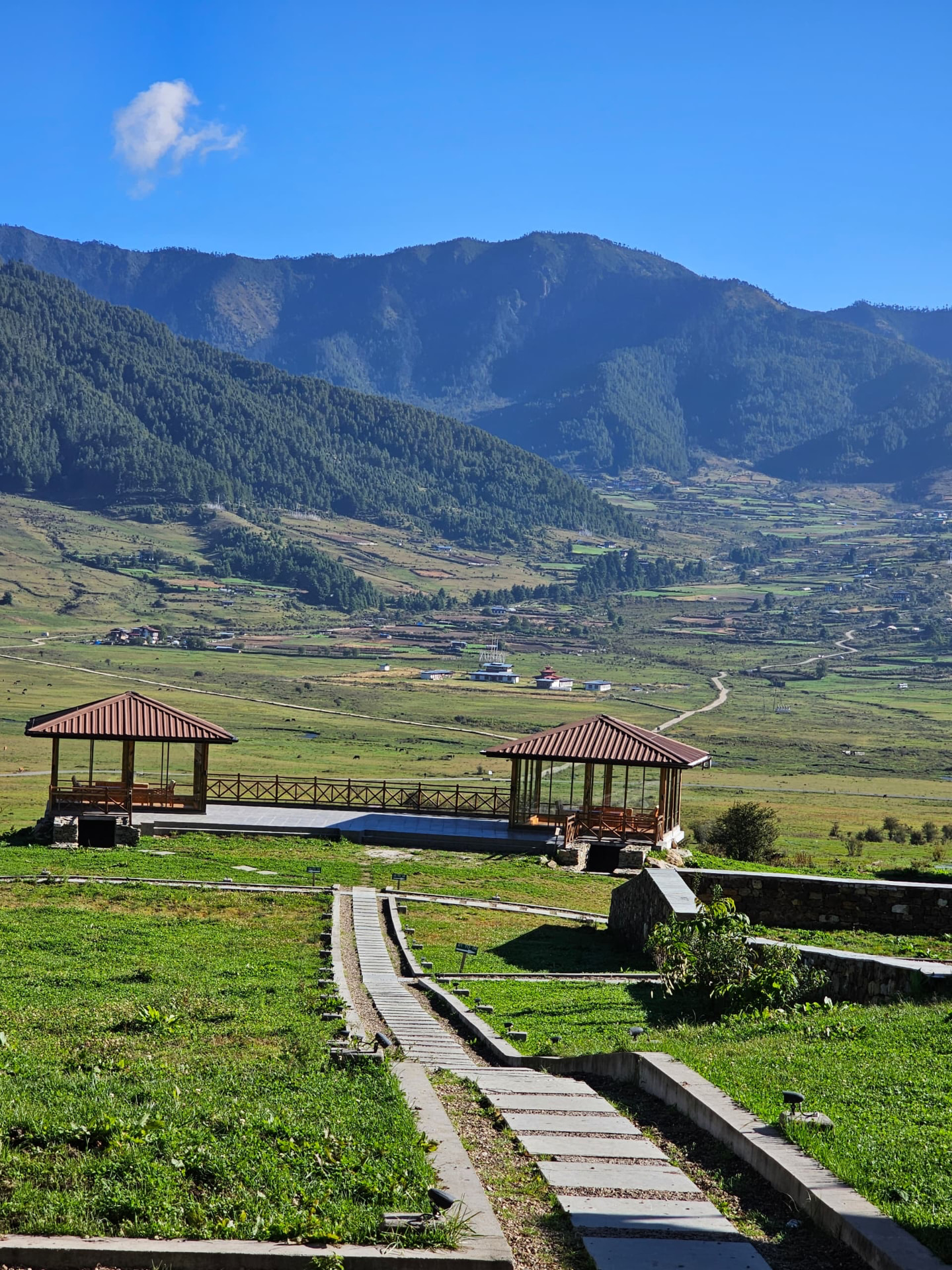 A green mountain valley with a scenic walkway and small roofed shelters
