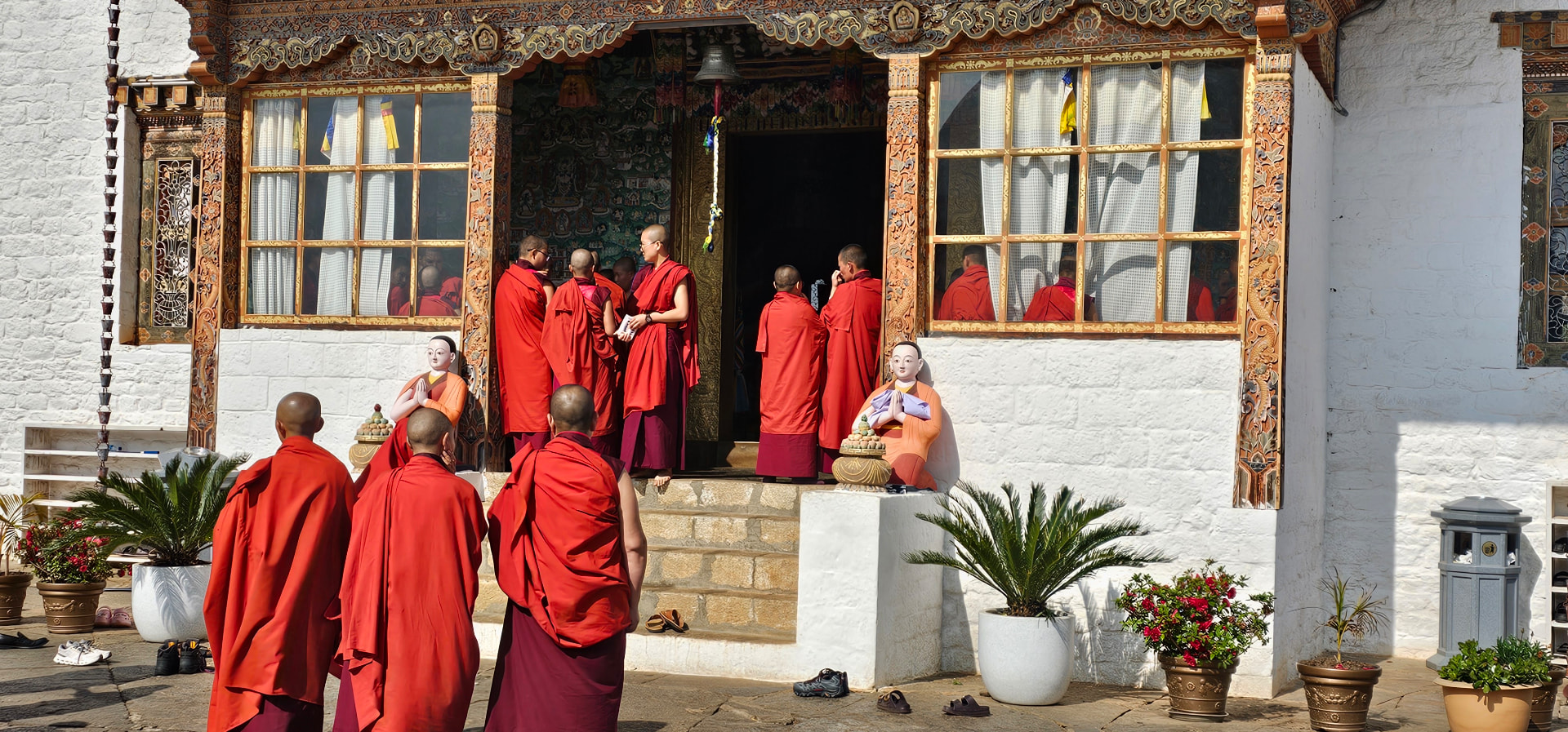 Monks in red robes gathered at the entrance to a richly decorated Bhutanese temple